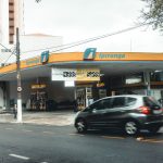 Posto de combustíveis Ipiranga com veículos em movimento em uma rua urbana.