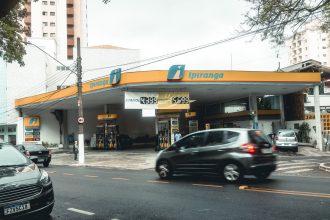 Posto de combustíveis Ipiranga com veículos em movimento em uma rua urbana.