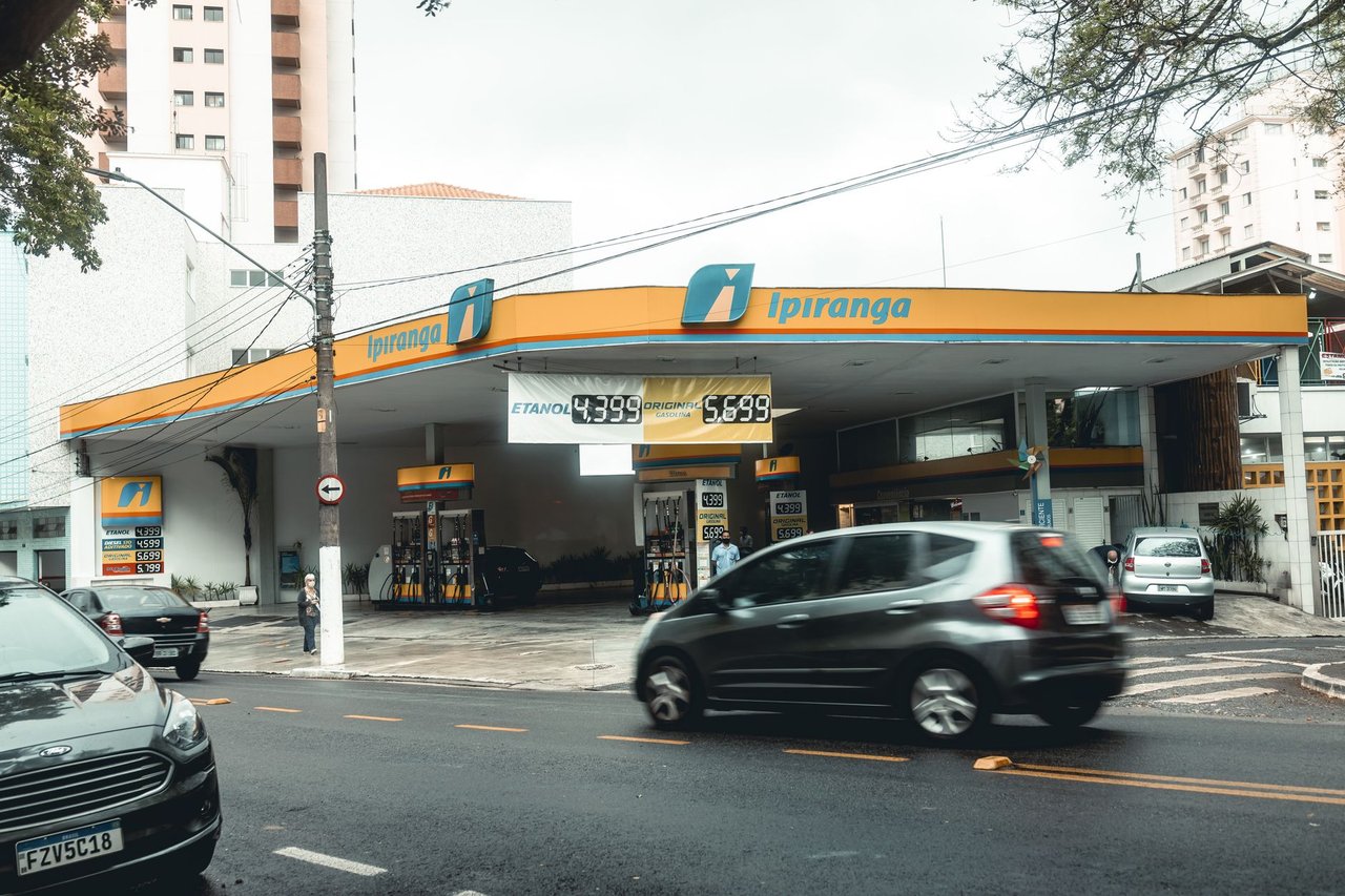 Posto de combustíveis Ipiranga com veículos em movimento em uma rua urbana.
